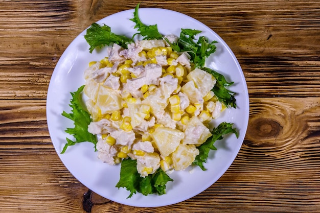 Festive salad with chicken breast, canned pineapple, cheese, sweet corn and mayonnaise on rustic wooden table. Top view