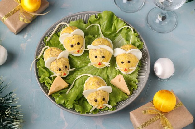 Festive snack Mice made of stuffed eggs with cod liver on a light blue background, Top view, Closeup