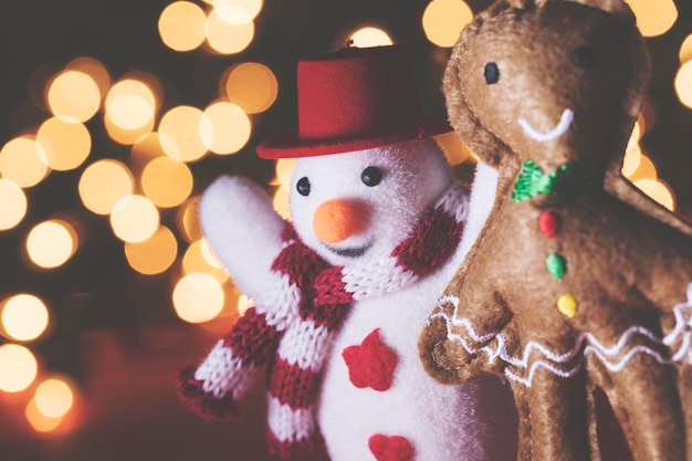 Festive snowman and gingerbread man decorations against a bokeh fairy light background