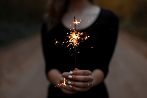 Festive sparkler. Women's hands hold a bright sparkler.