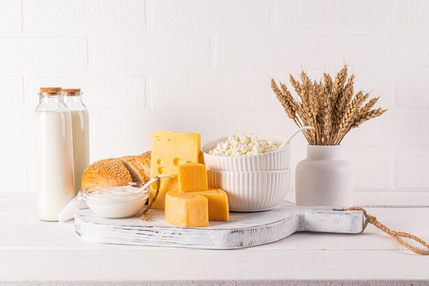 festive still life for the Jewish holiday of Shavuot Several types of cheese bottled milk grapes A white vase with ears of corn Front view