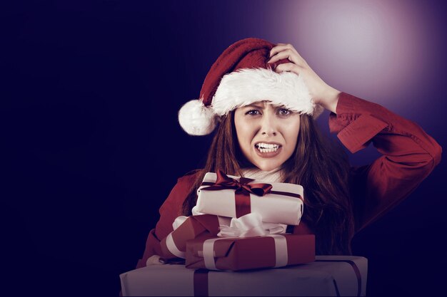 Festive stressed redhead holding gifts on white background