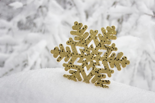 Festive surface golden sparkling decorative snowflake in winter real snow.