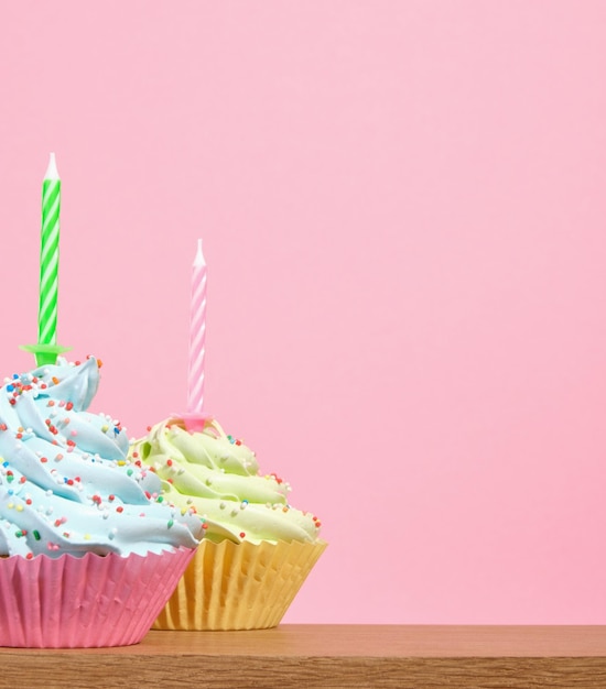 festive sweets on a pink background brightly colored cupcakes with holiday candles copy space for text