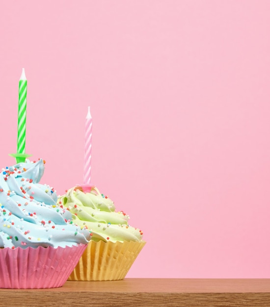 Festive sweets on a pink background Brightly colored cupcakes with holiday candles Copy space for text