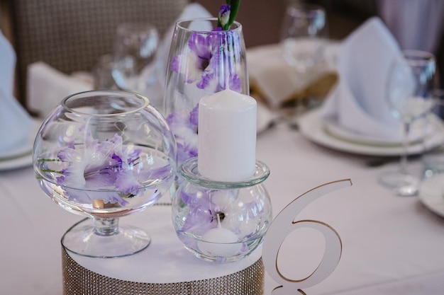 Festive table decorated with composition of violet purple flowers and greenery candles in the banquet hall Table newlyweds in the banquet area on wedding party