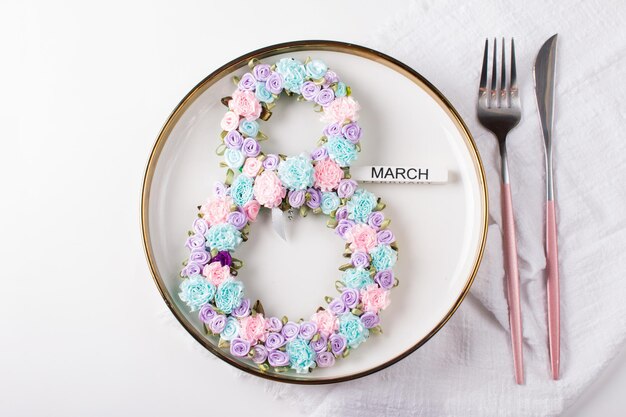 Festive table setting The number 8 decorated with flowers on a white plate Congratulations on the International Women's Day on March 8 a festive postcard banner