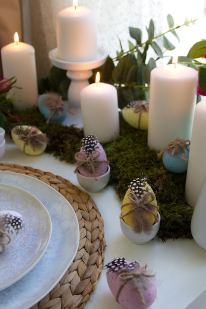 Festive table setting and spring decor with candles, easter eggs and flowers