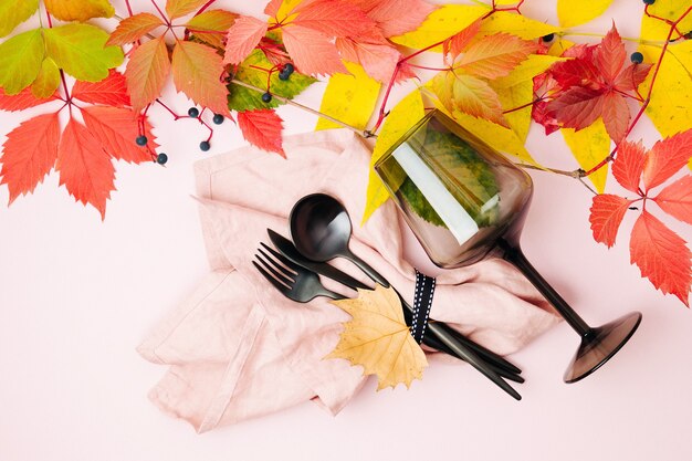 검은 접시와 와인 잔, 밝은 가을 잎이 있는 축제 테이블 설정