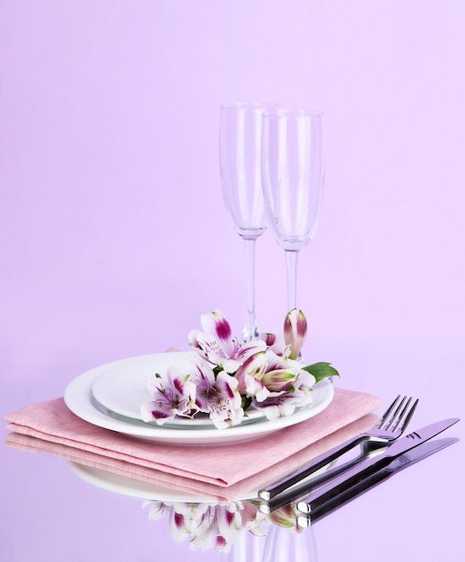 Festive table setting with flowers on lilac background