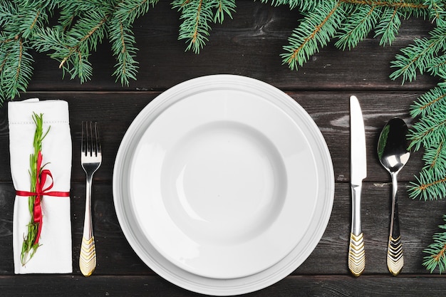 Festive table setting with pine tree branches on wooden background