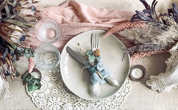 Festive table setting with sprigs of dried flowers and decorative elements.