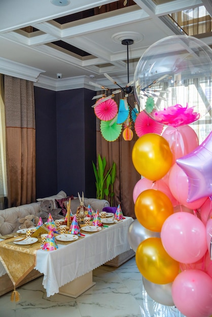 Festive table with decorations on the background of colored balloons.