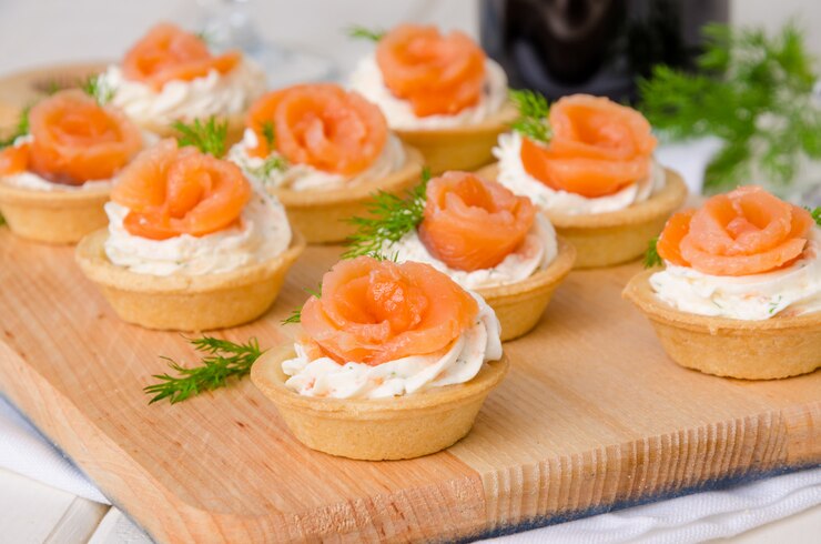 Photo festive tartlets with cream cheese, smoked salmon and dill served on a wooden board
