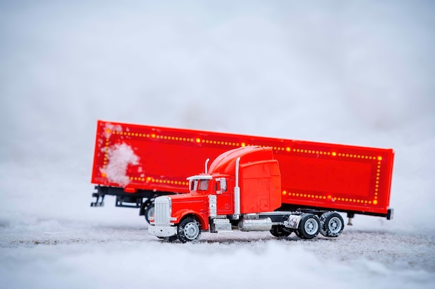 Festive truck in red toy car is standing with detached cargo container Winter Christmas holidays