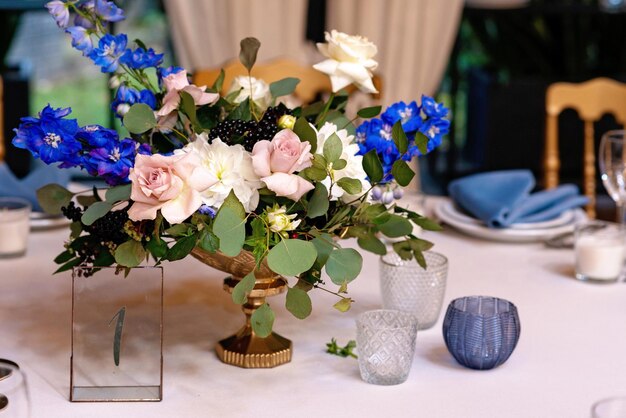 Festive wedding, table setting with blue linen napkins, candles and fresh flower bouquets. Wedding decorations. Restaurant menu concept. Soft selective focus.