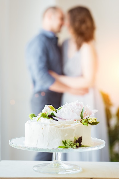 Festive white cake on a stand and a couple in love