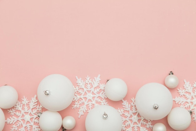 Festive winter composition White christmas balls and snowflakes on a pastel pink background