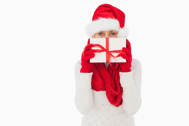 Festive woman looking at camera holding a gift