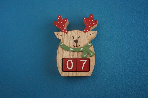 Festive wooden deer with Viva Magenta cubes 07 on blue background closeup top view Christmas concept of date or time Funny numbers 07 on red cubes Copy space for text or event Educational cubes