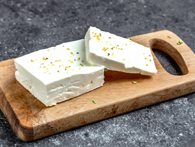 Photo feta cheese on a cutting board on a stone background