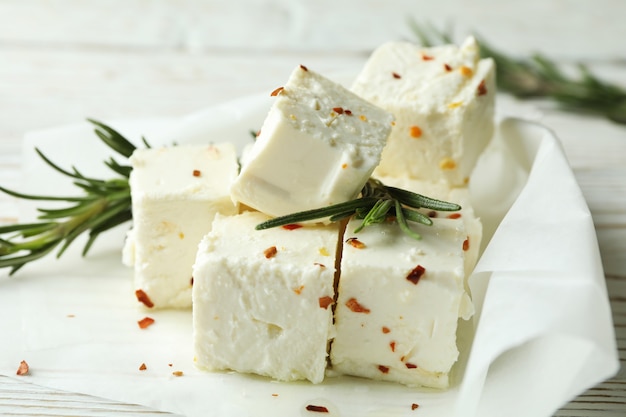 Feta cheese with spices and rosemary on white wooden background