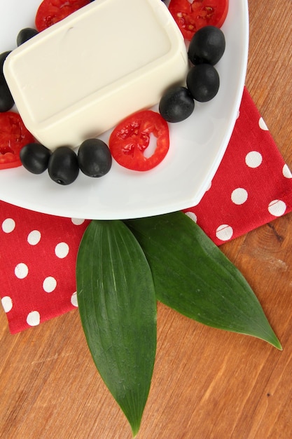 Fetakaas op bord versierd met olijven en tomaten op houten tafel close-up