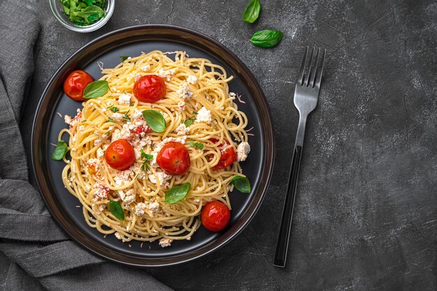 Fetapasta Populaire pasta met gebakken fetakaas, cherrytomaatjes, kruiden en knoflook op een donkere achtergrond Bovenaanzicht ruimte om te kopiëren