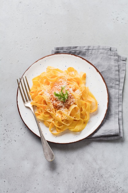 Fettuccine pasta met Parmezaanse kaas in lichte plaat op oude witte betonnen ondergrond. Bovenaanzicht.