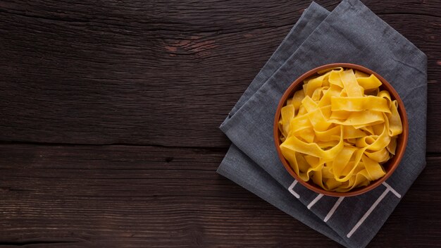 Fettuccine pasta on a wooden table in a bowl. Top view. Vegetarian food.