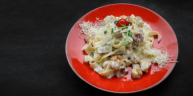 Fettuccine with chicken and mushrooms on a dark background