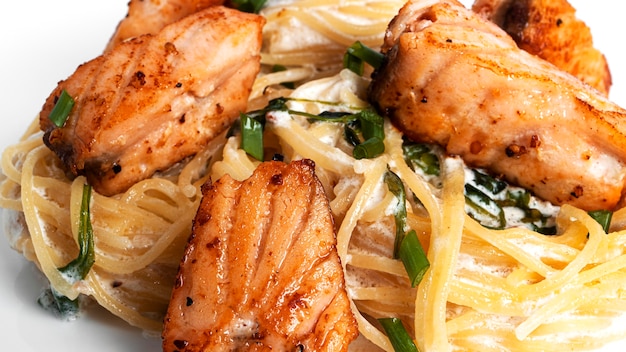 Fettuccine con salmone e rucola in salsa di panna isolata. nidi di pasta isolati.