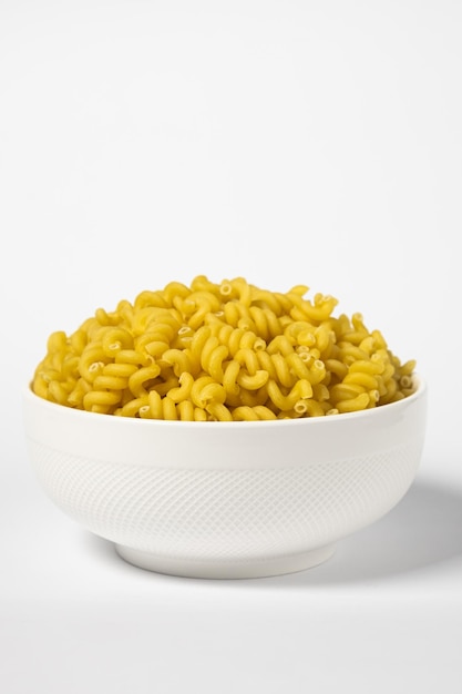 Few Cavatappi Cellentani nest in a plate on yellow background