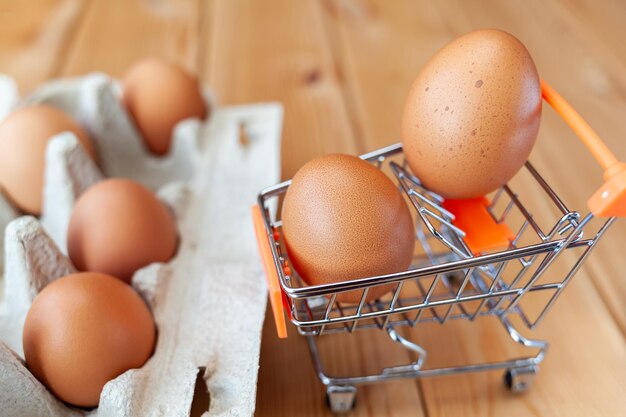 A few chicken eggs in the shopping basket next to cardboard bag an important food item