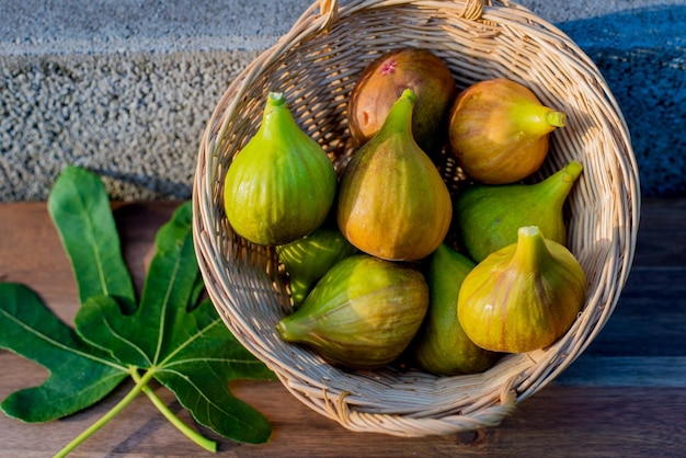 A few figs in wicker basket on concrete background in sunshine