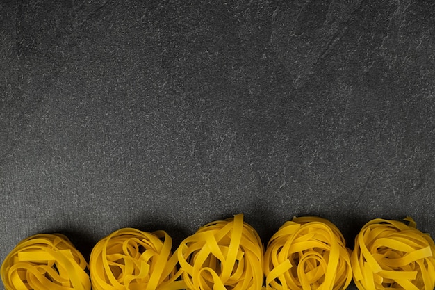 Few homemade fettuccine nest isolated on dark background