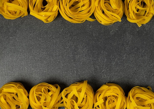 Few homemade fettuccine nest isolated on dark background