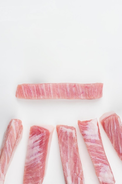 A few pieces of pork ribs are laid out on a white surface.