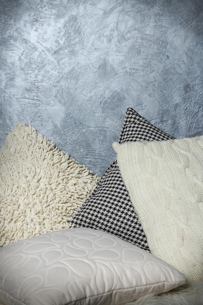 Few pillows on grey wall background closeup