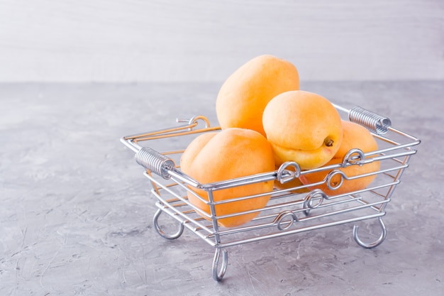 A few ripe apricots in a metal basket on a table