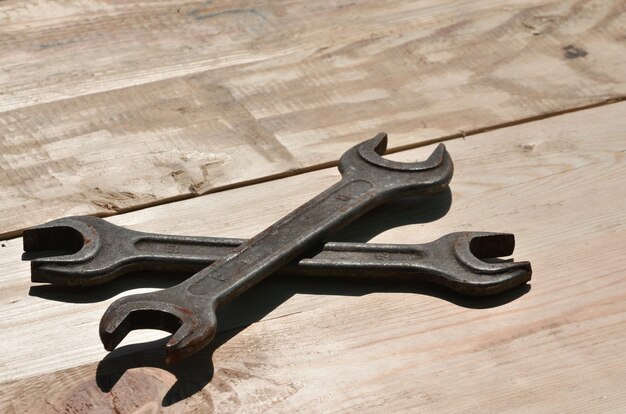 A few rusty spanners lies on a wooden table in a workshop