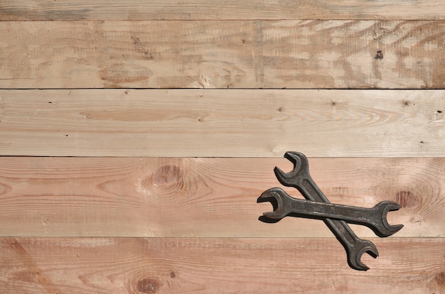 A few rusty spanners lies on a wooden table in a workshop