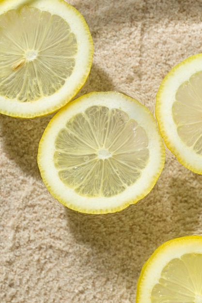 A few slices of fresh lemon floating on water sand on the background close up look