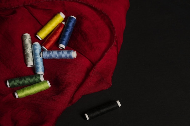 A few spools of colored sewing threads on a red cloth