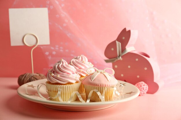 Few tasty cupcakes with decorations on pink background