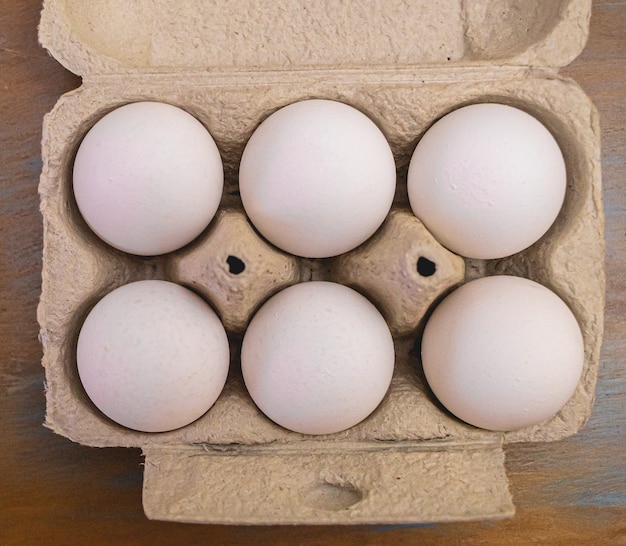 a few white raw chicken eggs in a small tray on a wooden table