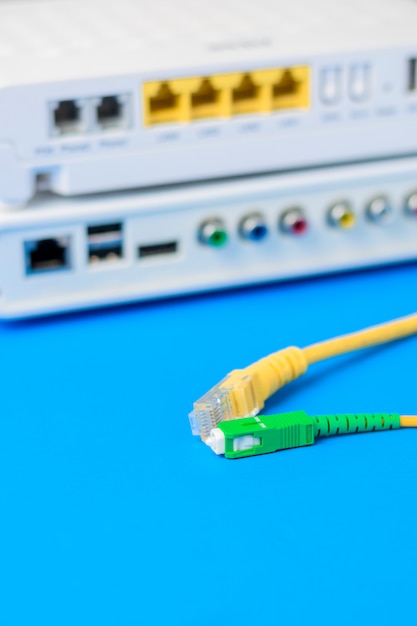 Fiber optical and network cables with internet wireless router on a blue background