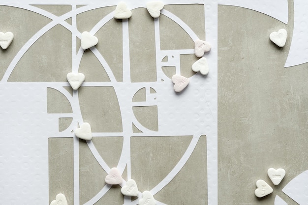 Fibonacci sequence circles and sugar hearts on beton stone background Sweet taste perfection Golden ratio concept Top view geometric paper art Desaturated earth colored white beige colors