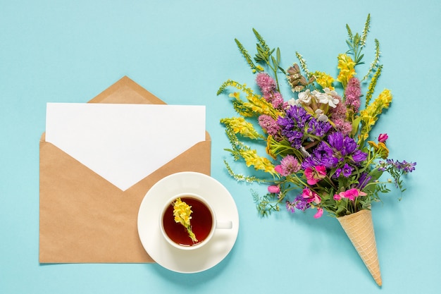 Fiori di campo, busta artigianale e tazza di tè alle erbe