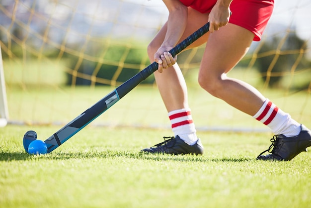 Field hockey sports and training with a player hitting a ball with a stick and practicing for a match or sport event Closeup of a sporty athlete being active healthy and fit while running outside